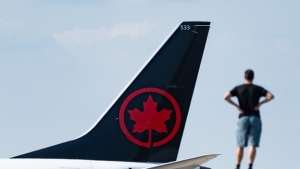 A person watches as an Air Canada plane lands at Montreal-Pierre Elliott Trudeau International Airport in Montreal, Friday, Sept. 13, 2024. THE CANADIAN PRESS/Christinne Muschi
