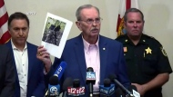 Palm Beach County Sheriff Ric Bradshaw holds up a photo that shows two backpacks hanging on a fence and a GoPro camera that were said to be near Donald Trump's golf club in West Palm Beach, Fla.