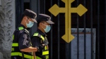 Security officers on patrol walk past the gates of the Catholic Wangfujing Church in Beijing on Sept. 14, 2022. (Mark Schiefelbein / AP Photo)