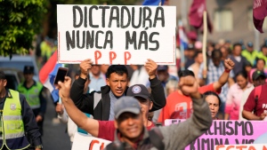 An anti-government protester holds a sign with a message that reads in Spanish, 'Dictatorship never again,' during an opposition rally, marking a year since President Santiago Pena's inauguration, in Asuncion, Paraguay, Thursday, Aug. 15, 2024. (AP Photo/Jorge Saenz) 