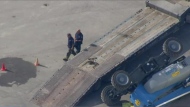 A piece of construction equipment lies on its side next to a flatbed truck following a fatal industrial accident at Ontario Place Tuesday September 17, 2024. 