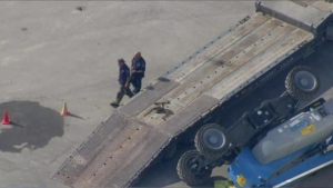 A piece of construction equipment lies on its side next to a flatbed truck following a fatal industrial accident at Ontario Place Tuesday September 17, 2024. 