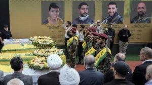 Hezbollah fighters salute as they stand next to the coffins of four victims who were killed Tuesday after their handheld pagers exploded, during their funeral procession in the southern suburb of Beirut, Lebanon, Wednesday, Sept. 18, 2024. (AP Photo/Bilal Hussein)