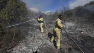 Israeli firefighters work to extinguish a fire after a rocket fired from Lebanon hit an open field in northern Israel, Wednesday, Sept. 18, 2024. (AP Photo/Baz Ratner)