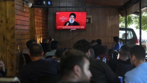 People watch the speech of Hezbollah leader Hassan Nasrallah on a tv screen as they sit in a cafe in the southern suburbs of Beirut, Thursday, Sept. 19, 2024. (AP Photo/Hassan Ammar)