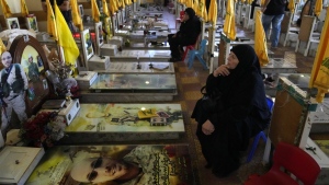 Women sit in a cemetery as they visit the graves of killed Hezbollah members in the southern suburbs of Beirut, Thursday, Sept. 19, 2024. (AP Photo/Hussein Malla)