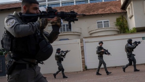 Israeli security forces search for assailants near the scene of a deadly car-ramming and stabbing attack at a bus stop, in Ra'anana, Israel, Monday, Jan. 15, 2024. (AP Photo/Oded Balilty)