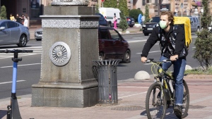 A delivery cyclist wearing a face mask cycles down a street in Kyiv, Ukraine, Friday Sept. 20, 2024 on a day with poor air quality. (AP Photo/Tony Hicks)