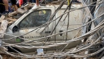 People stand on top of a damaged car at the scene of a missile strike in the southern suburbs of Beirut, Friday, Sept. 20, 2024. (AP Photo/Bilal Hussein)