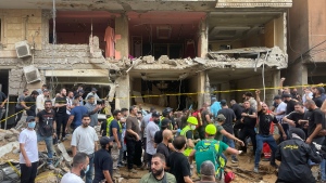 People gather near a damaged building at the scene of an Israeli missile strike in the southern suburbs of Beirut, Friday, Sept. 20, 2024. (Bilal Hussein / The Associated Press)