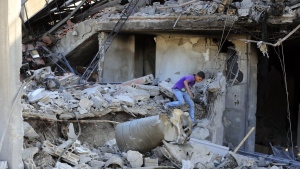 A boy checks the damage to a building hit in an Israeli airstrike in the southern village of Akbieh, Lebanon, Tuesday, Sept. 24, 2024. (AP Photo/Mohammed Zaatari)