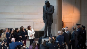 Daughter Rosanne Cash, center left, accompanied by other family members, looks up at the unveiling of a bronze statue of singer Johnny Cash, created by Little Rock sculptor Kevin Kresse, in Emancipation Hall at the Capitol in Washington, Tuesday, Sept. 24, 2024. (AP Photo/Ben Curtis)