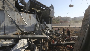 People gather at the site of an Israeli airstrike that hit a hangar in the southern town of Jiyeh, Lebanon, Wednesday, Sept. 25, 2024. (AP Photo/Mohammed Zaatari)