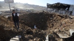 A Lebanese police intelligence stands near a crater at the site of an Israeli airstrike that hit a hangar in the southern town of Jiyeh, Lebanon, Wednesday, Sept. 25, 2024. (AP Photo/Mohammed Zaatari)