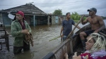 Neighbours chat on a flooded street after the passage of Hurricane Helene in Guanimar, Artemisa province, Cuba, Wednesday, Sept. 25, 2024. (AP Photo/Ramon Espinosa)