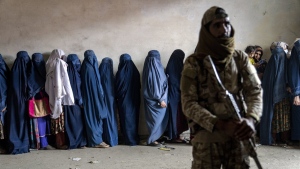 A Taliban fighter stands guard as women wait to receive food rations distributed by a humanitarian aid group in Kabul, Afghanistan, Tuesday, May 23, 2023. (AP Photo/Ebrahim Noroozi, File)