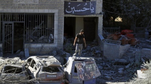 A man stands on top of a damaged car at the site of an Israeli airstrike in Saksakieh, south Lebanon, Thursday, Sept. 26, 2024. THE CANADIAN PRESS/AP/Mohammed Zaatari