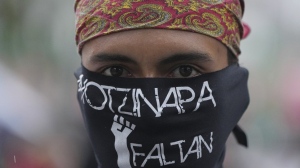 A masked youth takes part in a demonstration marking the 10-year anniversary of the disappearance of 43 students from an Ayotzinapa rural teacher's college, in Mexico City, Thursday, Sept. 26, 2024. (AP Photo/Fernando Llano)