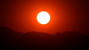 FILE: The setting sun illuminates the sky over the Rocky Mountains as a wildfire burns. (David Zalubowski / The Associated Press)