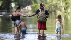 Dustin Holmes, second from right, holds hands with his girlfriend, Hailey Morgan, while returning to their flooded home with her children Aria Skye Hall, 7, right, and Kyle Ross, 4, in the aftermath of Hurricane Helene, Friday, Sept. 27, 2024, in Crystal River, Fla. (AP Photo/Phelan M. Ebenhack)