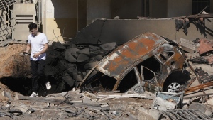 A man walks on rubble at the site of an Israeli airstrike in Beirut's southern suburbs, Sunday, Sept. 29, 2024. (AP Photo/Hassan Ammar)