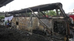 A rescuer inspects a bus that caught fire, carrying young students with their teachers, in suburban Bangkok, Tuesday, Oct. 1, 2024. (AP Photo/Sakchai Lalit)