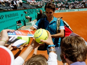 Switzerland's Roger Federer signs autographs after defeating Australia's Peter Luczak during their first round match of the French Open tennis tournament at the Roland Garros stadium in Paris, Monday, May 24, 2010. (AP Photo/Christophe Ena)