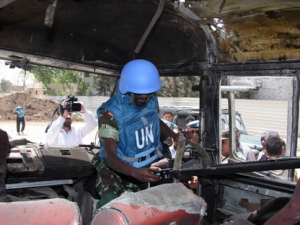 A U.N. observer takes pictures of a military bus that was damaged by a roadside bomb, at al-Bahdaliyah area, near Damascus, Syria, Wednesday, May 23, 2012. Syria's uprising began in March 2011 with mostly peaceful calls for reform, but the government's brutal crackdown on dissent led many in the opposition to take up arms. The U.N. estimates more than 9,000 people have been killed as the conflict spirals toward civil war. (AP Photo/Bassem Tellawi)