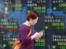 A women walks past an electronic stock indicator in Tokyo on Wednesday, May 23, 2012. (AP Photo/Shizuo Kambayashi)