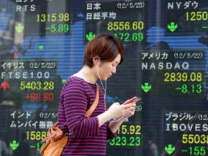 A women walks past an electronic stock indicator in Tokyo on Wednesday, May 23, 2012. (AP Photo/Shizuo Kambayashi)