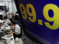 Money traders work under a screen flashing the euro being quoted below 100 yen on the foreign exchange market in Tokyo on Thursday, May 24, 2012. Worries over Greece intensified after European leaders adjourned a summit without taking concrete measures to prevent Europe's debt crisis from exploding and Greece from making a messy exit from the region's shared currency. (AP Photo/Shizuo Kambayashi)