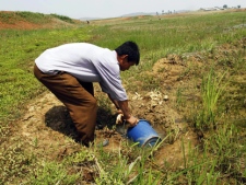 In this May 25, 2012, photo, a North Korean farmer gathers water as he tries to irrigate a field at the Tokhae cooperative farm on the outskirts of Nampho, North Korea. (AP Photo/Kim Kwang Hyon)