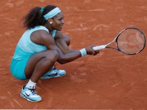 Serena Williams of the U.S. squats on the clay in her first round match against Virginie Razzano of France at the French Open tennis tournament in Roland Garros stadium in Paris on Tuesday, May 29, 2012. (AP Photo/Christophe Ena)