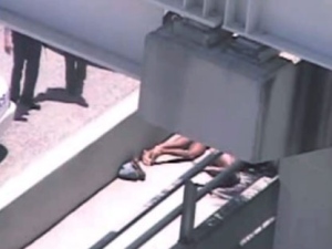 In this image taken from video, Miami police officers stand watch near a naked man, second from right, who was shot dead by a police officer when he refused to stop chewing on the face of the naked man next to him, partially obscured by a railing, on the MacArthur Causeway ramp onto Northeast 13th Street in Miami on Saturday, May 26, 2012. (AP Photo/The Miami Herald)