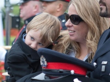 Erin Ochakovsky holds her four-year-old son Owen as they have their photo taken beside a Peel Regional Police officer holding a Peel Regional hat in memory of Const. James Ochakovsky, who died on March 2, following the annual Canadian Police and Peace Officers' Memorial Service on Parliament Hill in Ottawa on Sunday, September 26, 2010. (THE CANADIAN PRESS/Pawel Dwulit)